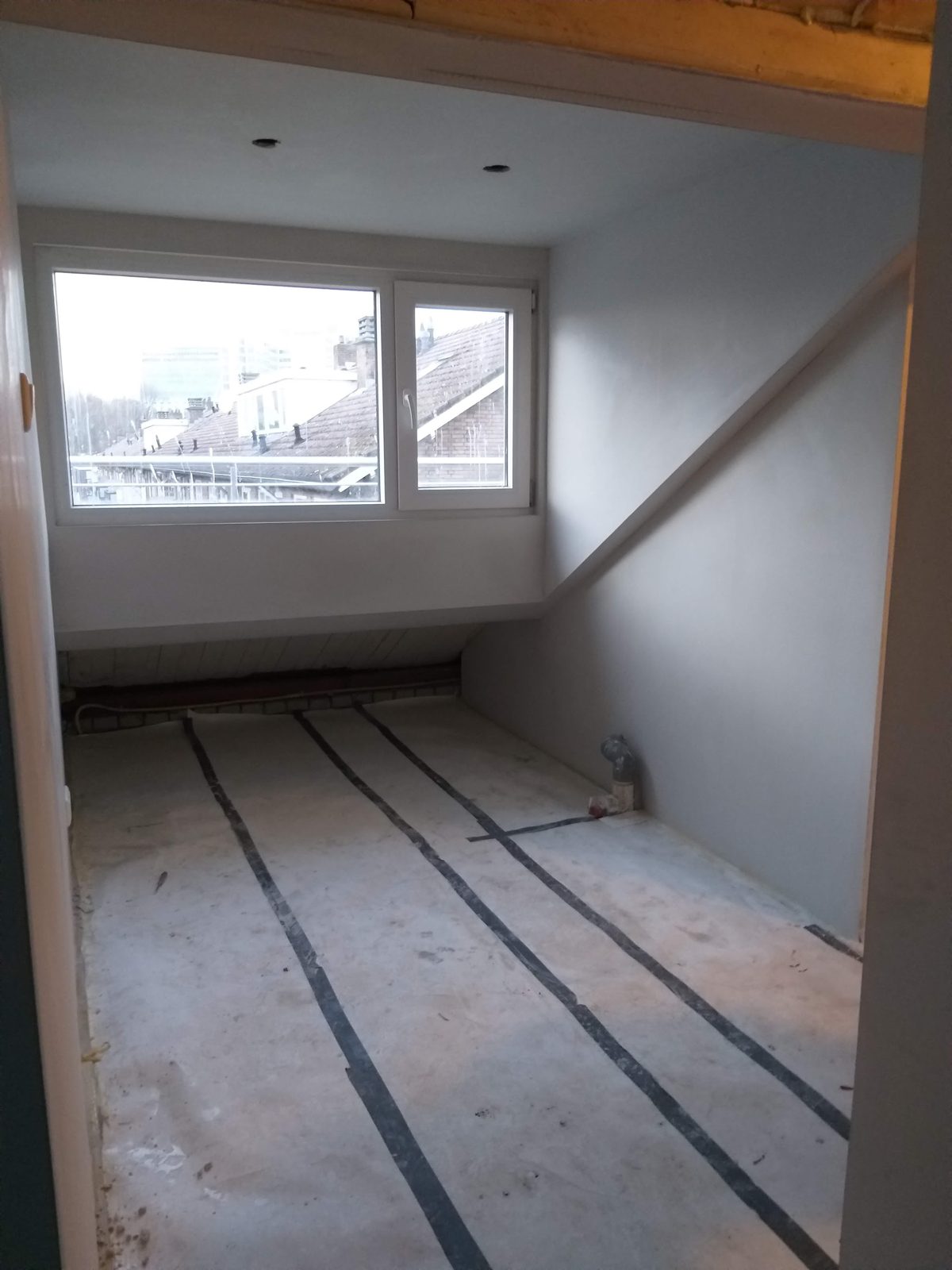 Kamer onder een dakkapel met nieuw raam, afgewerkte wanden en een voorbereide vloer