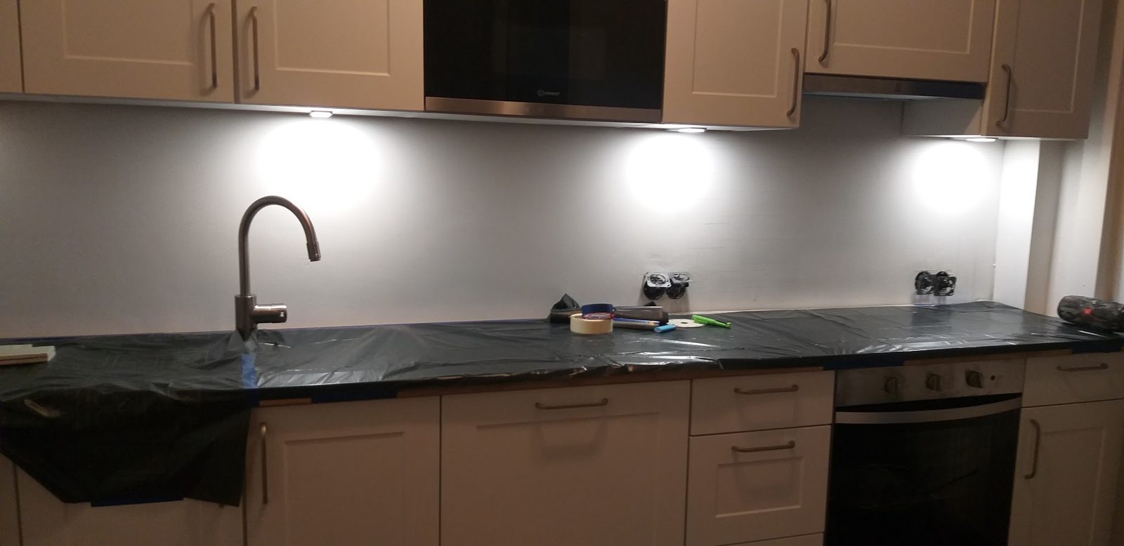 Keukenblad met verlichte bovenkasten, zwarte kraan en oven