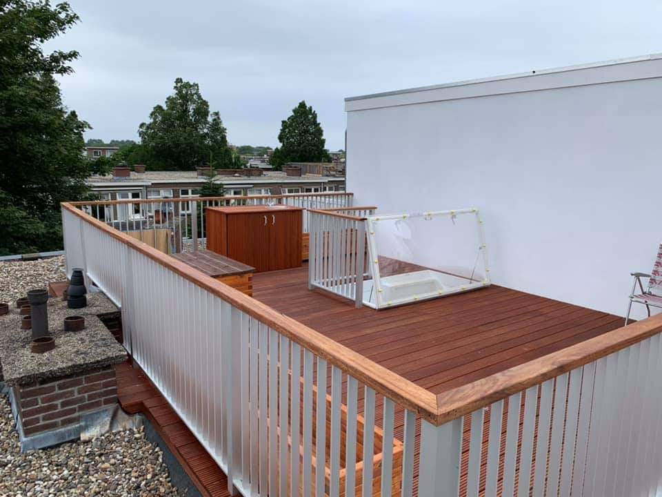 Hardhouten dakterras met wit hekwerk op een plat dak