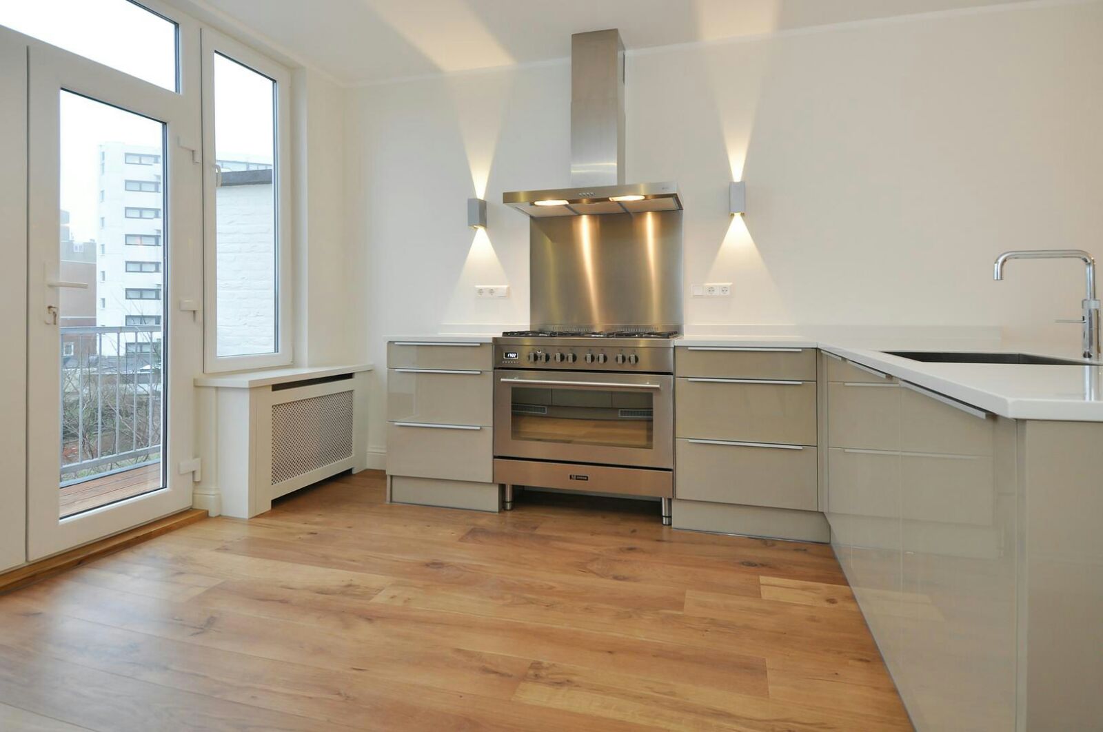 Keuken met fornuis, rvs afzuigkap, wandlampen en houten vloer